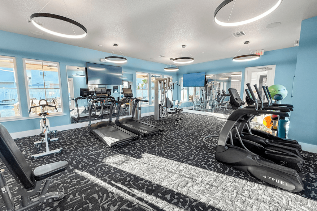 A gym with a variety of equipment including treadmills, weights, and exercise machines.