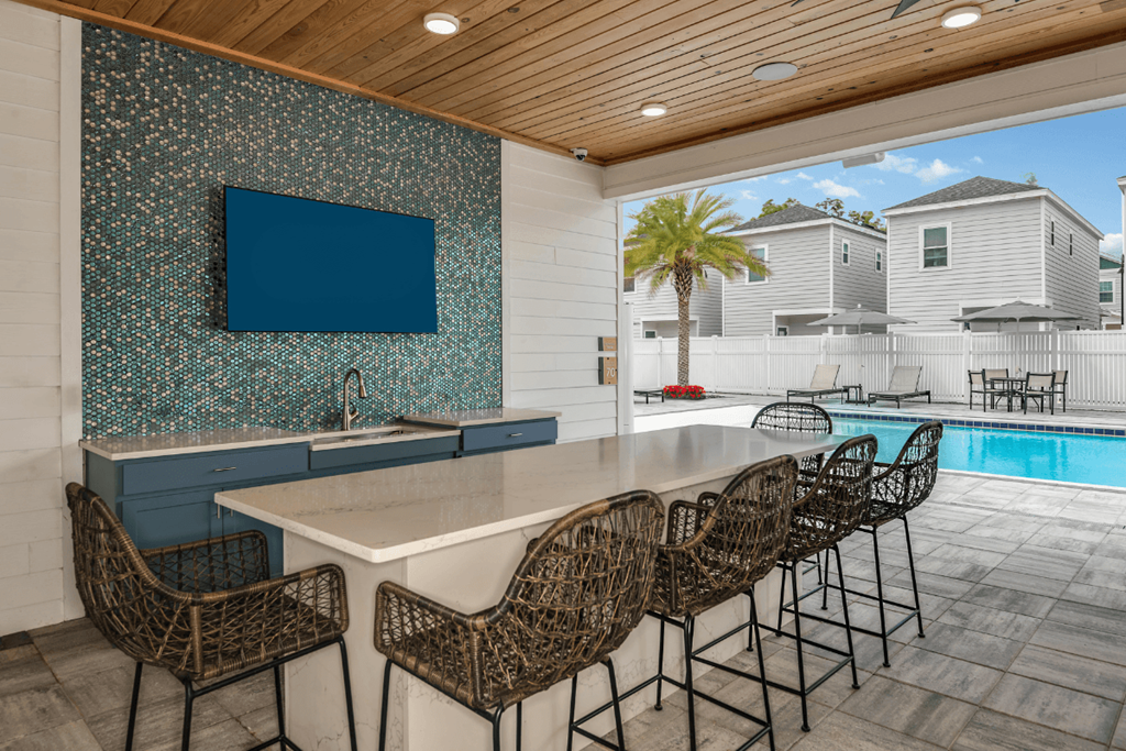 A kitchen with a blue backsplash and a television mounted above the counter.