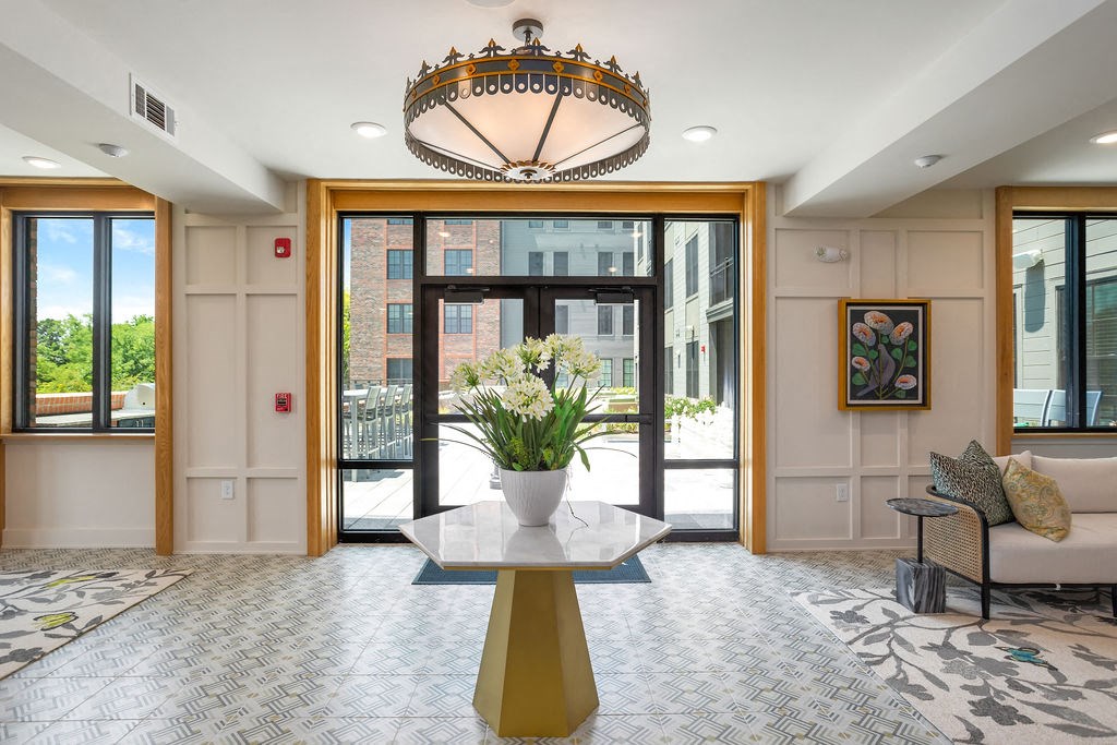 a lobby with a large glass door and a table with flowers