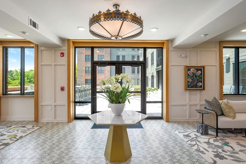 a lobby with a large glass door and a table with flowers