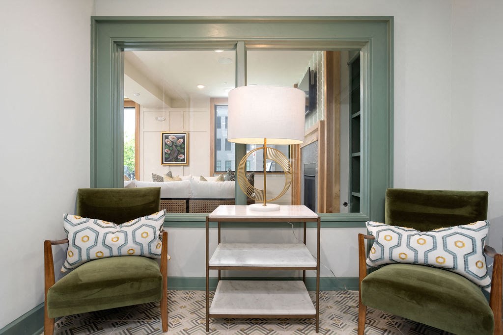 a living room with green chairs and a table and a window