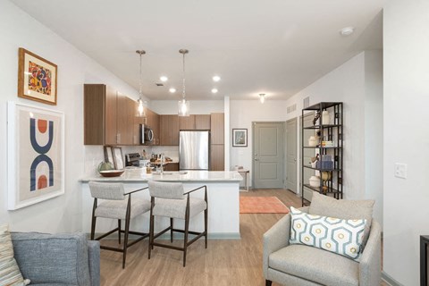 an open kitchen and living room with a bar and chairs