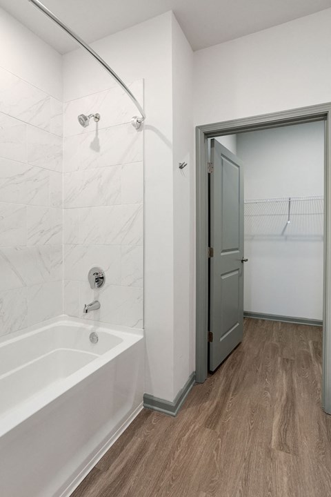 a white bathroom with a shower and a door to a closet