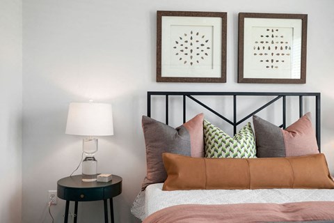 a bedroom with a bed with pillows and pictures on the wall