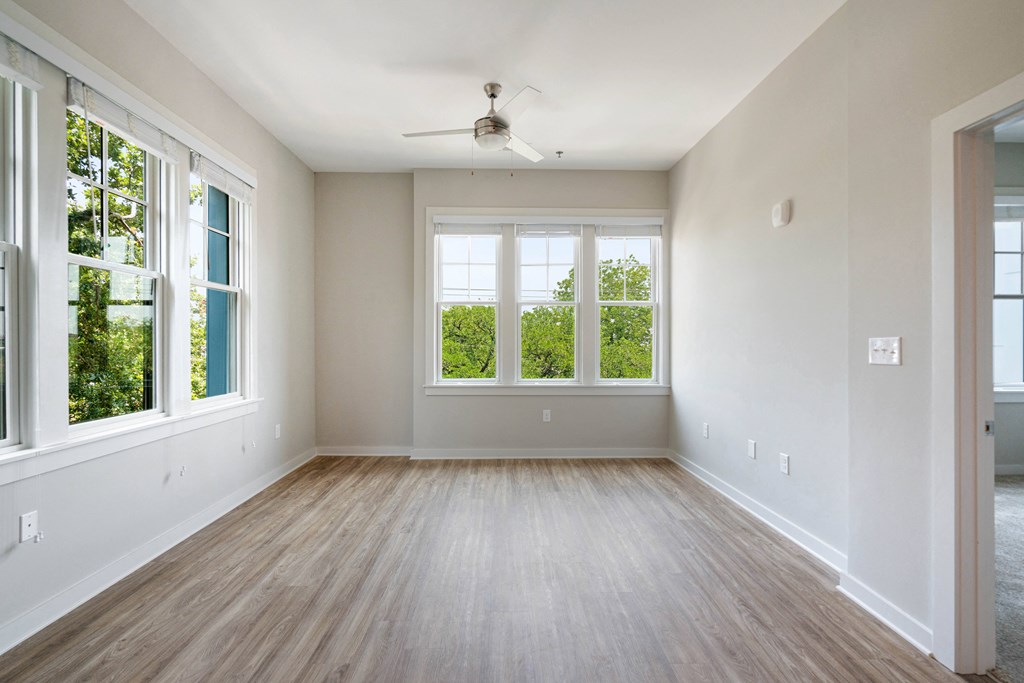 an empty living room with wood floors and a ceiling fan