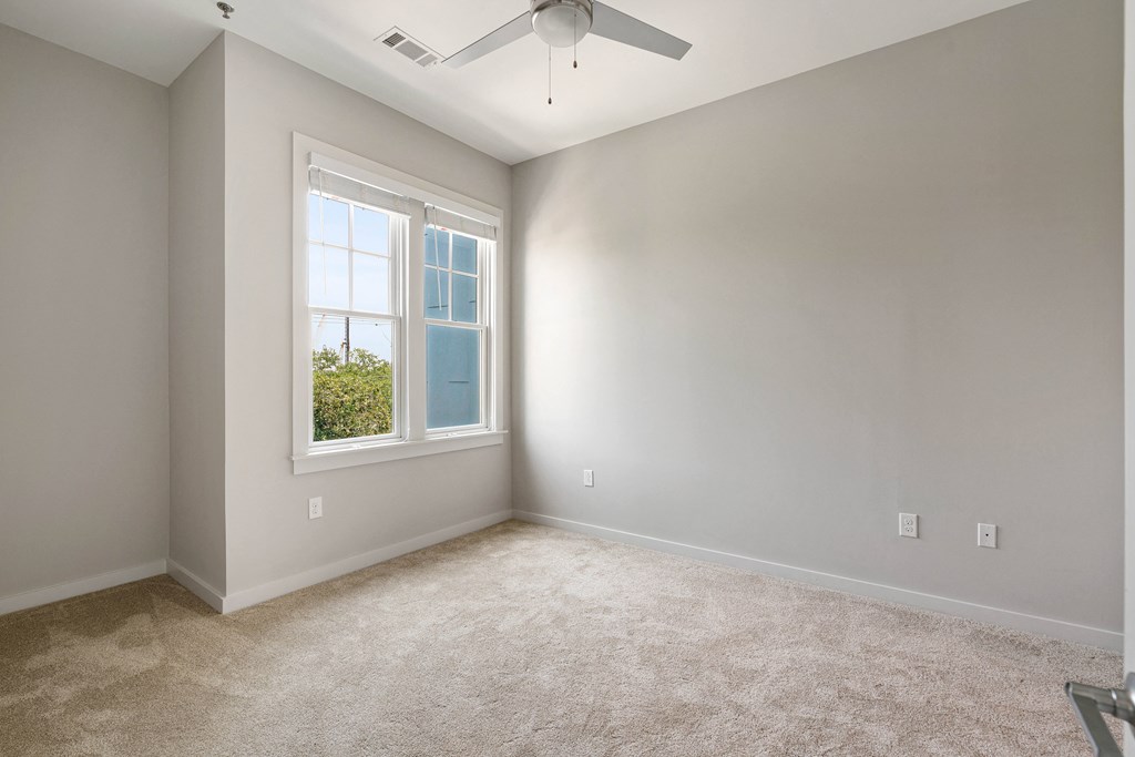 an empty room with a ceiling fan and a window