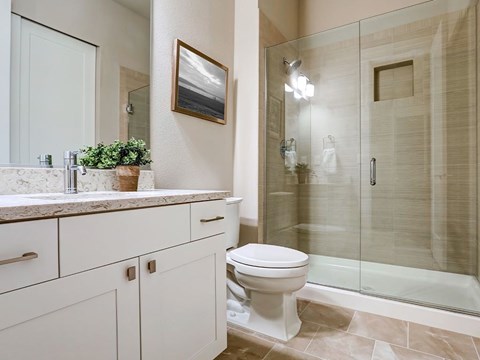 A white toilet sits in a bathroom with a walk-in shower.