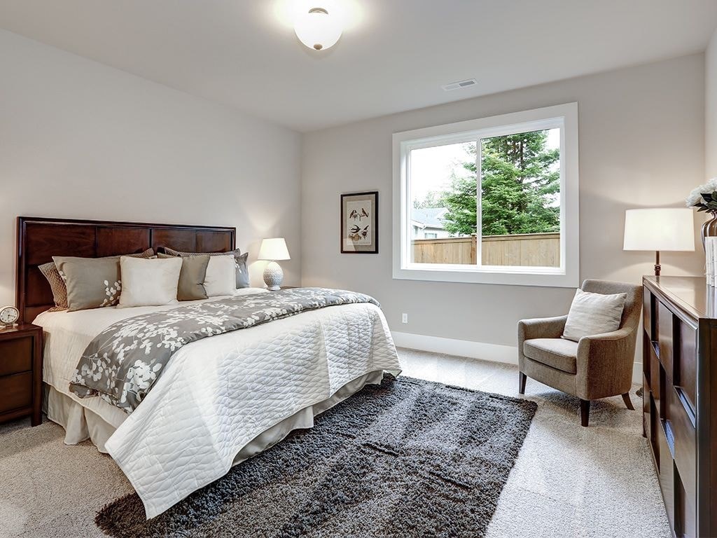 A bedroom with a large bed and a chair.