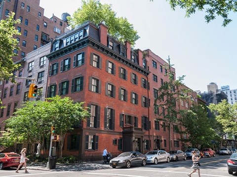 A red brick building with green shutters on the windows.