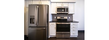 A modern kitchen with a stainless steel refrigerator and a black and white backsplash.