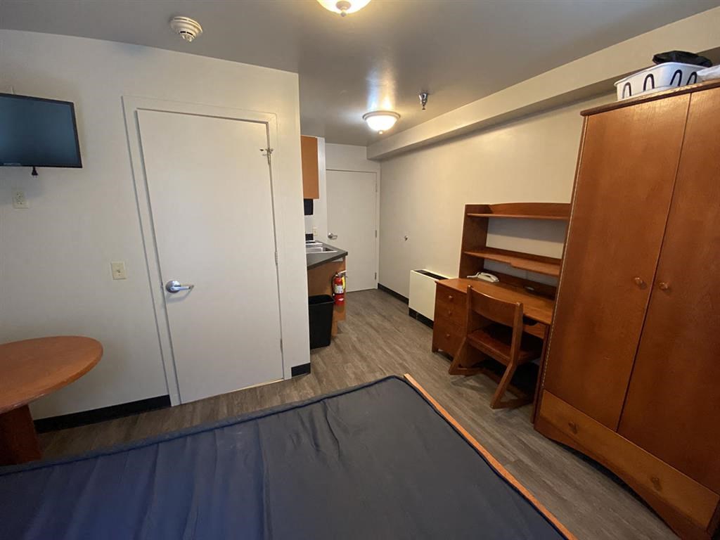 a room with a bed and a desk and a door