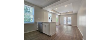 A kitchen with wooden floors and white cabinets.