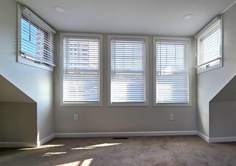 Three windows with blinds open in a room.