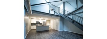an empty living room with a staircase  and a kitchen