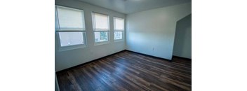 a empty room with a wooden floor and three windows