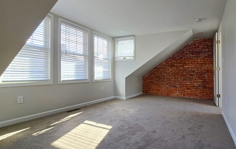 A room with a carpeted floor and a brick wall.
