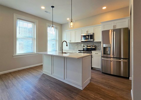 A kitchen with a stainless steel refrigerator and wooden floors.