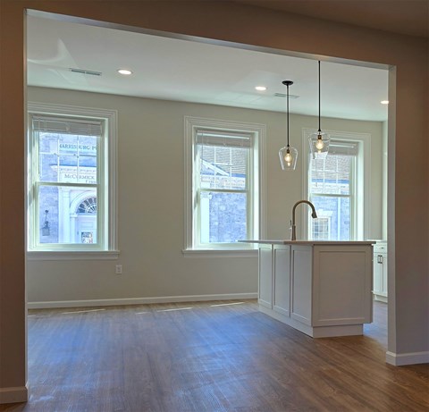 A kitchen with a white counter and wooden floors.