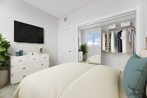 A bedroom with a large bed and a wardrobe with clothes hanging on it.