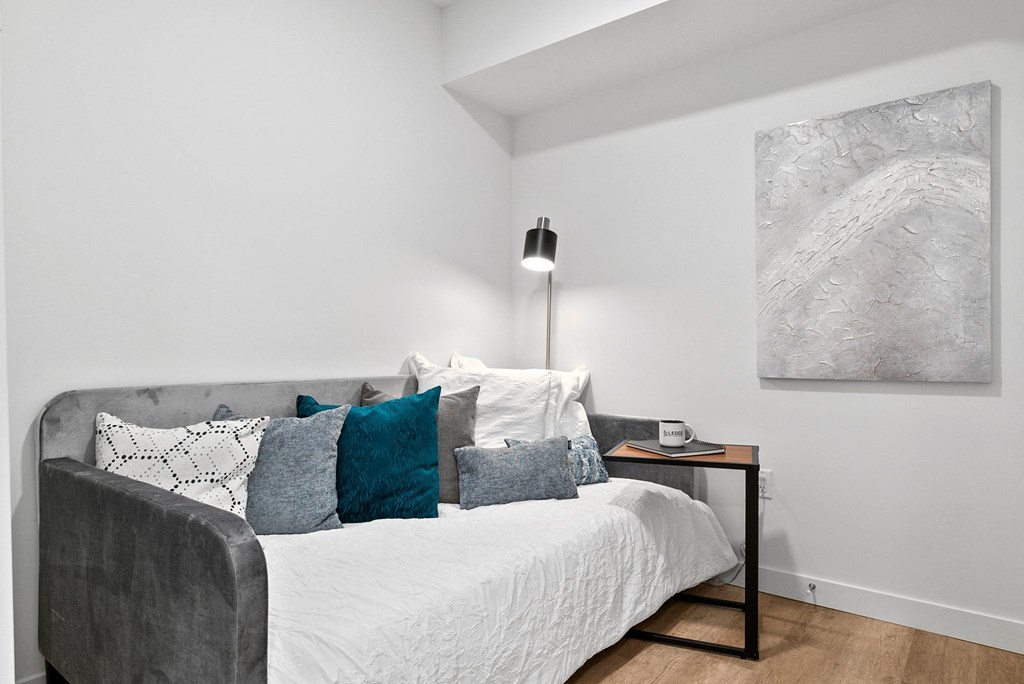 a bedroom with a bed and a nightstand with a clock and a painting on the wall