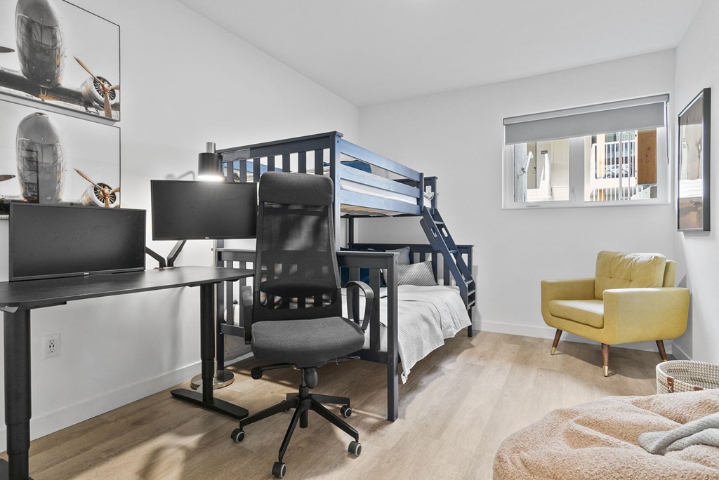 a bedroom with a bunk bed desk and chair