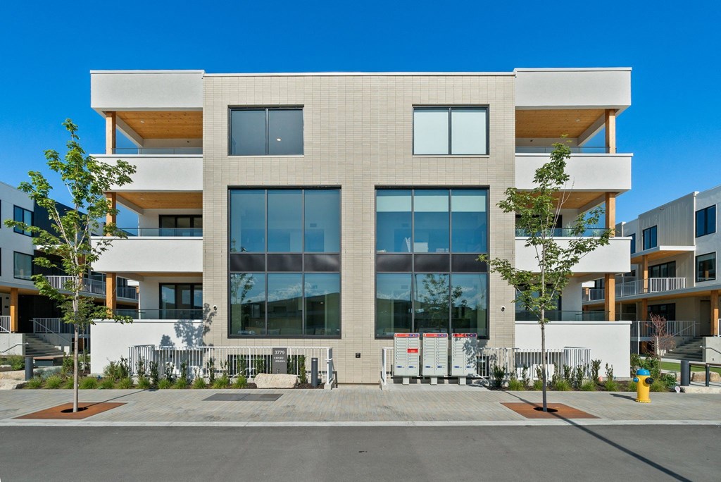 an apartment building with large windows and a sidewalk