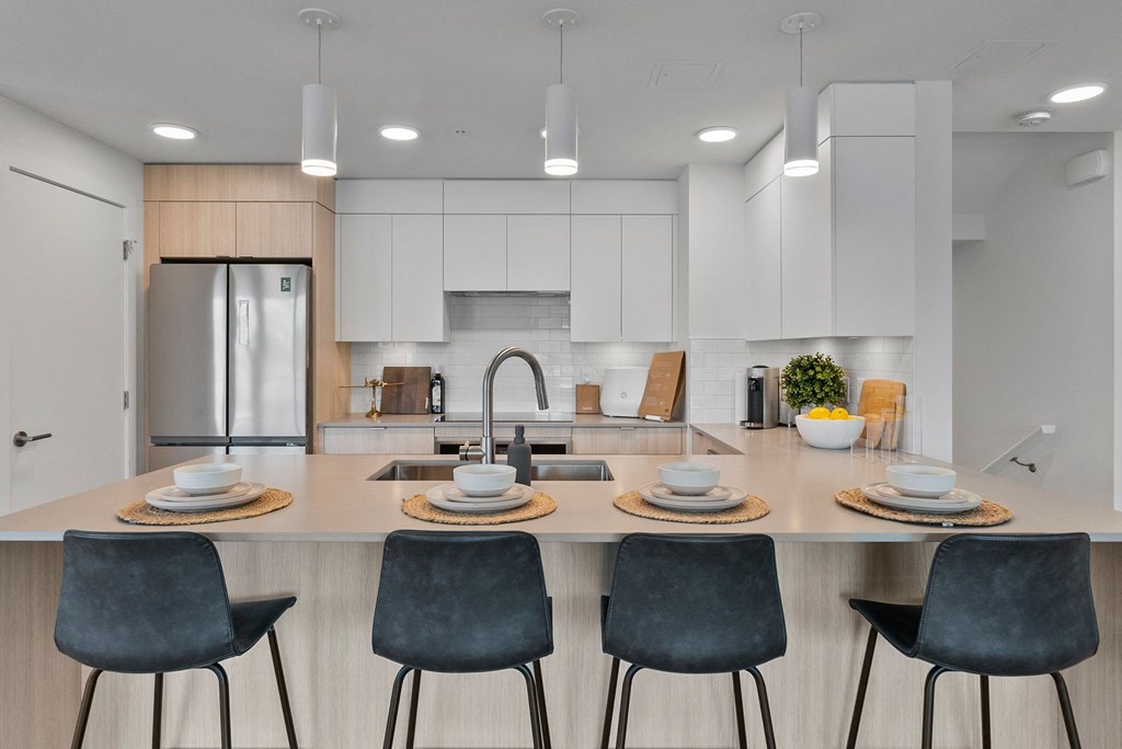 a kitchen with white cabinets and a large island with a sink and four chairs