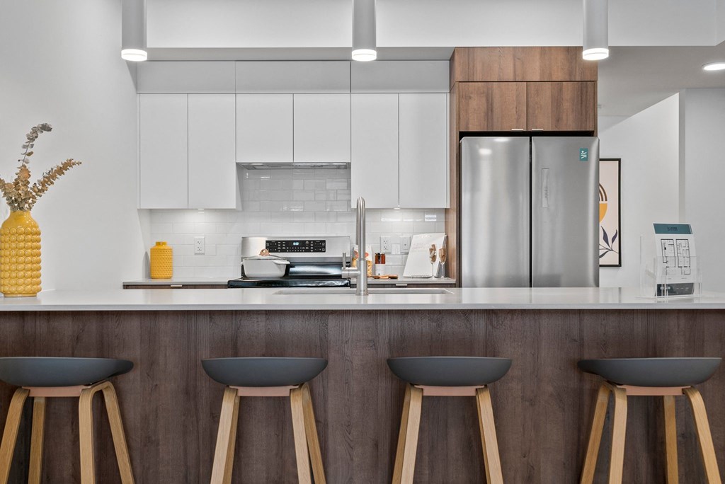 a kitchen with white cabinets and a large island with three stools in front of it