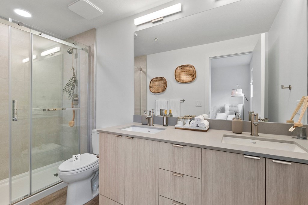 a bathroom with a toilet sink mirror and shower in a 555 waverly unit