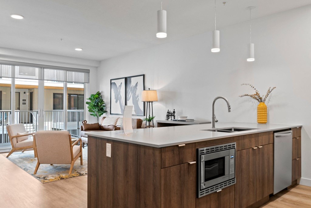 a kitchen with an island in front of a living room with a couch and chairs