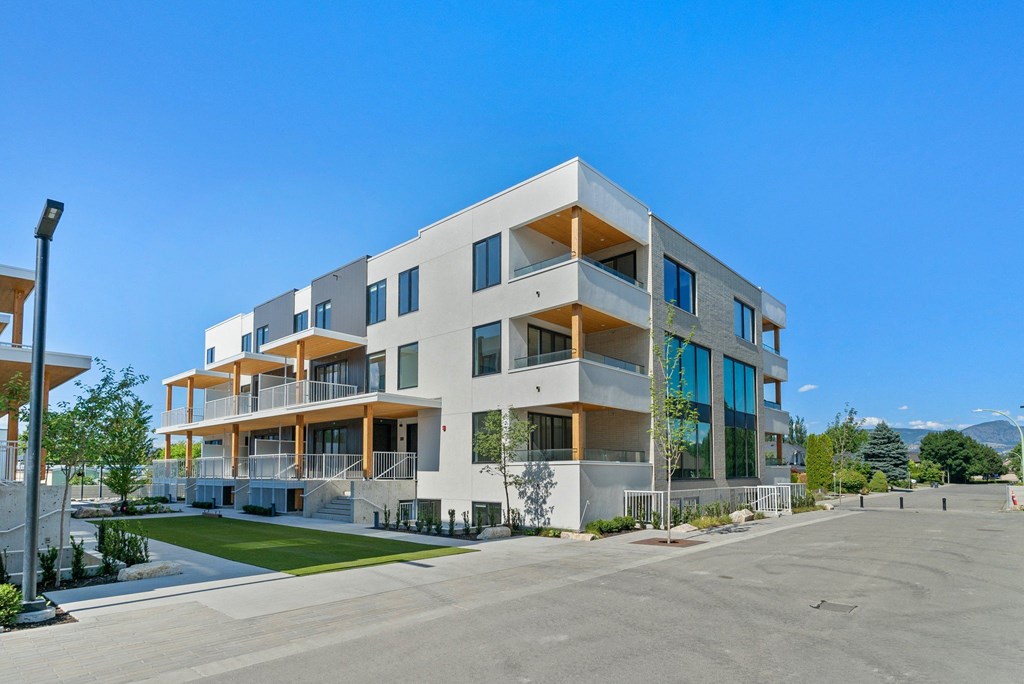 a large white apartment building with balconies and a lawn