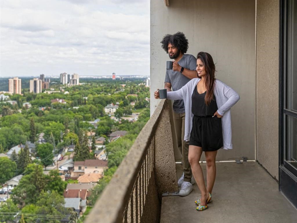 a man and woman standing on a balcony overlooking a city
