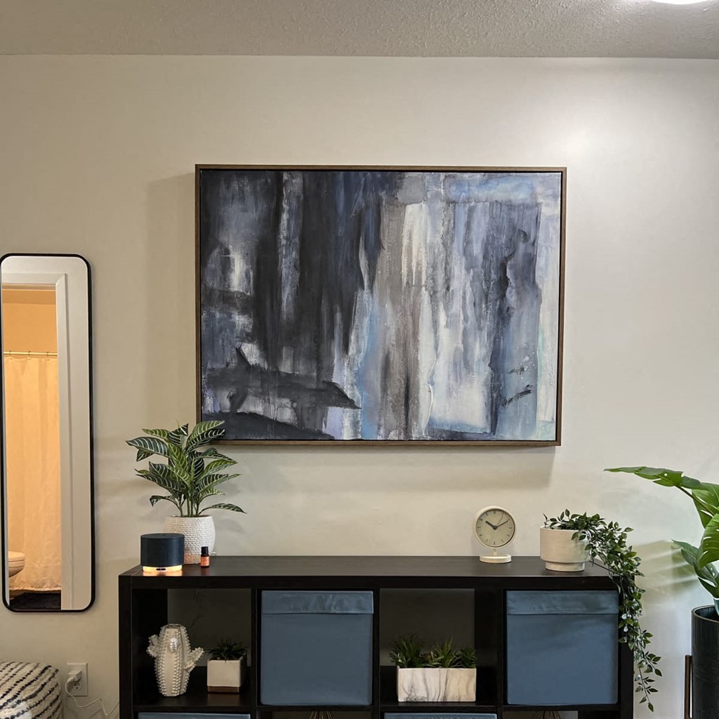 a painting hanging on a wall above a shelf in a room