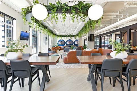 A modern dining area with wooden tables and grey chairs.