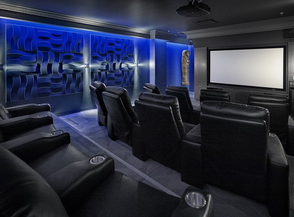 a cinema room with black leather chairs and a television