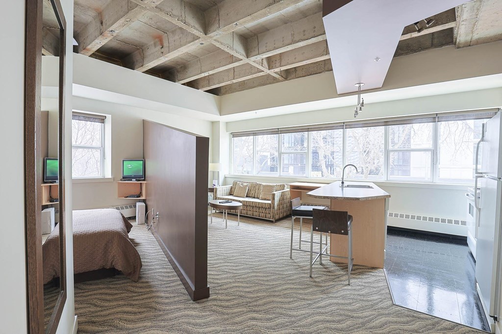 a bedroom with a bed and a kitchen in a room