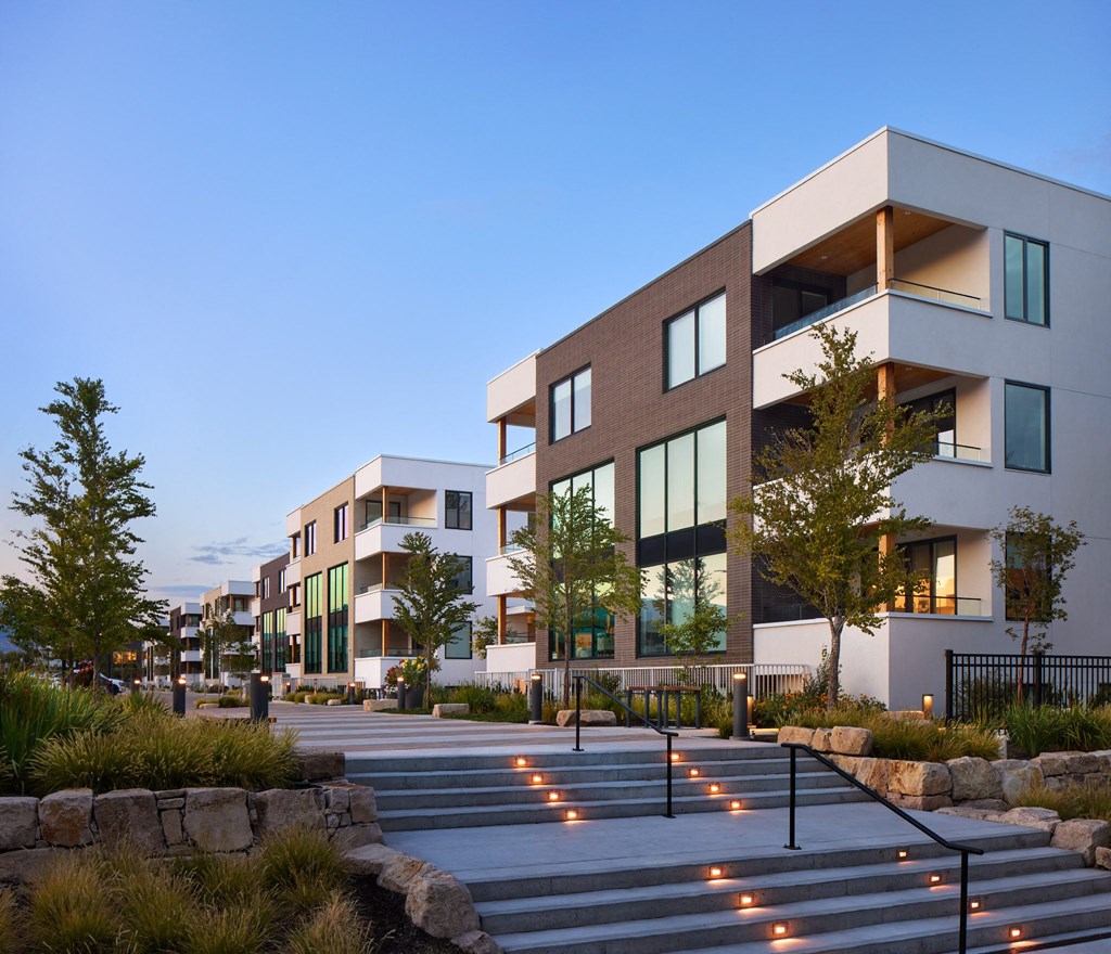 A modern building with a lot of windows and a stone wall in front.