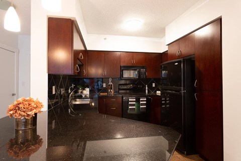 A kitchen with dark wood cabinets and black appliances.