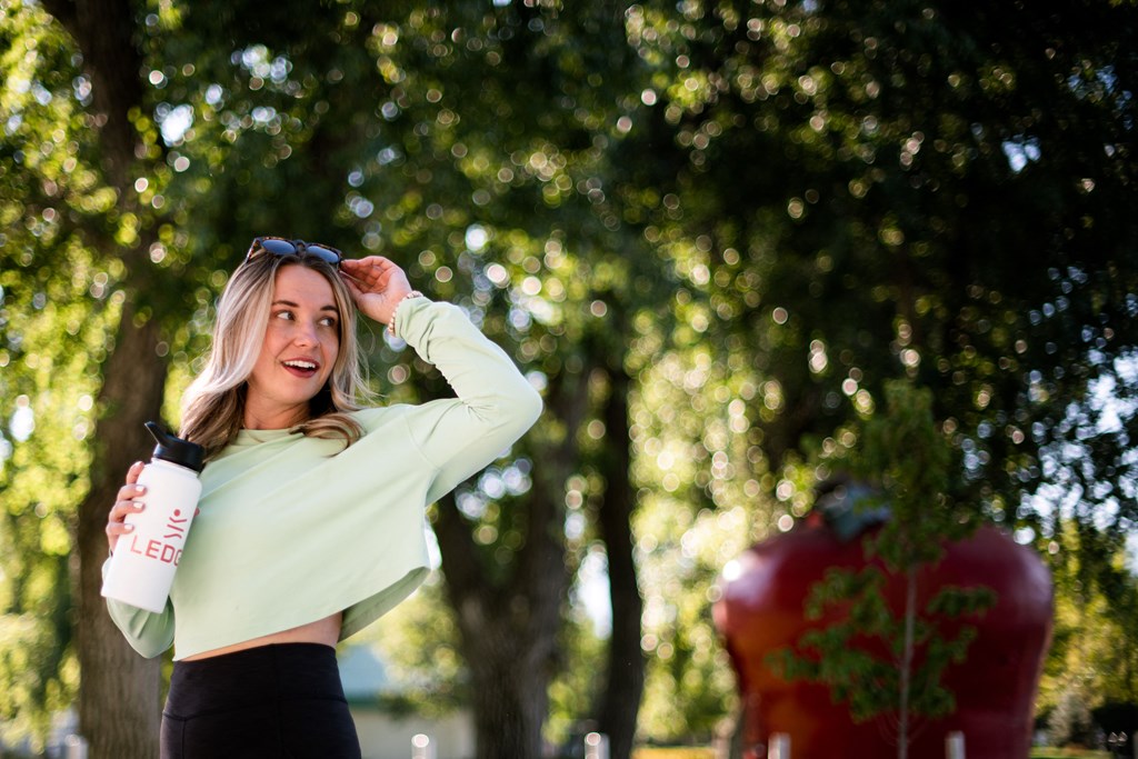 a woman standing in a park holding a bottle of water