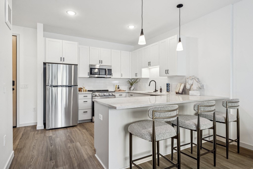 A kitchen with a white counter top and a stainless steel refrigerator.