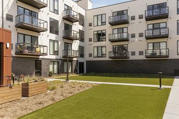 an exterior view of an apartment building with a yard and grass