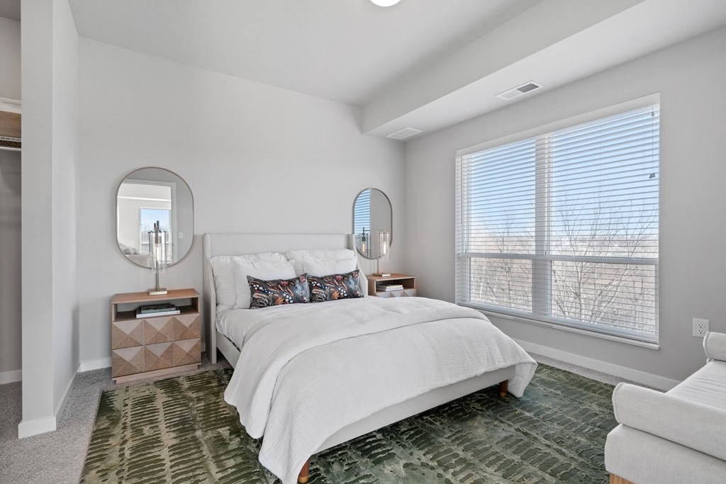 a white bedroom with a large window and a bed