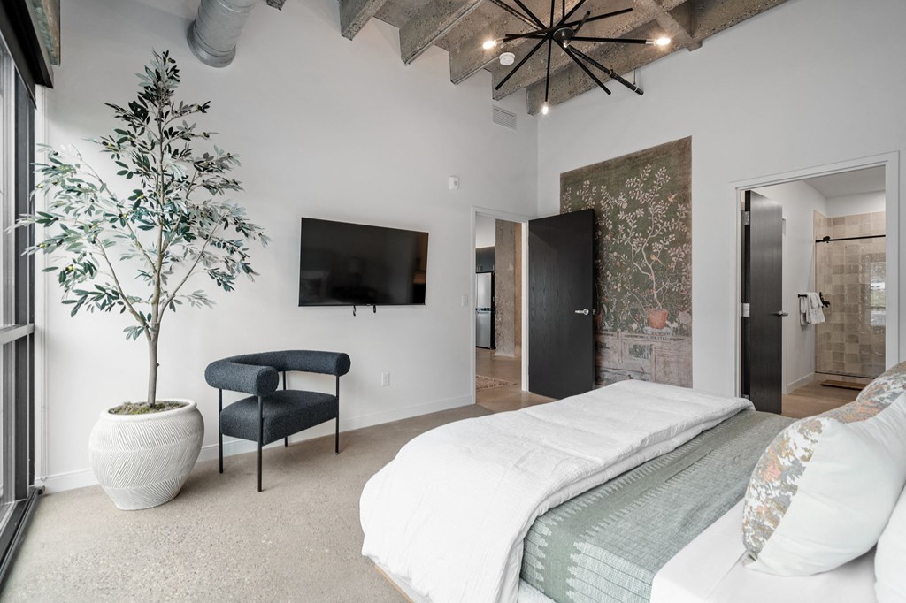 a bedroom with a bed and a chair and a tv