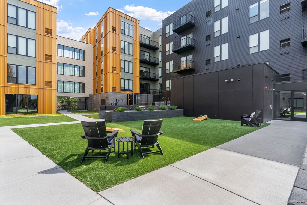 Two chairs are on a lawn in front of a building.