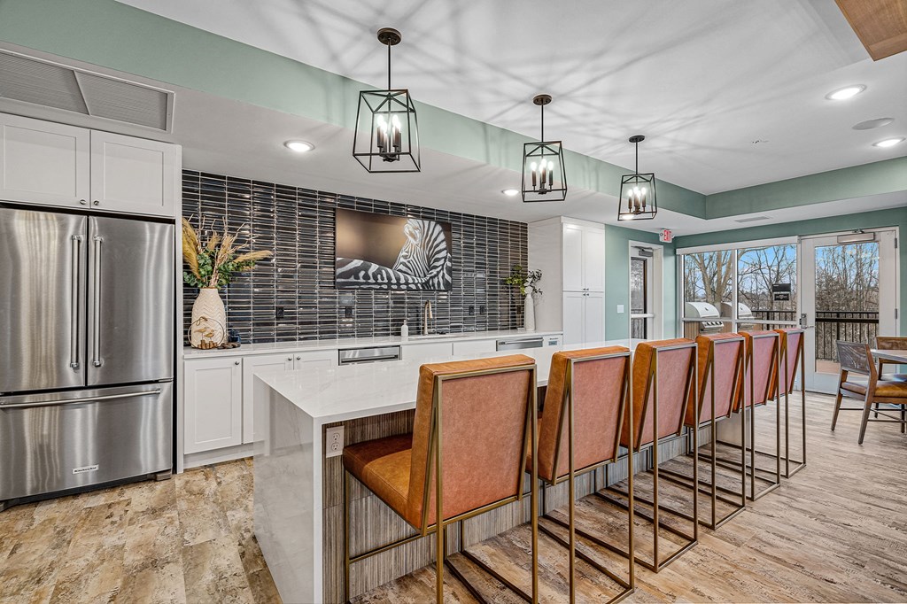 a kitchen with a long counter and chairs and a refrigerator