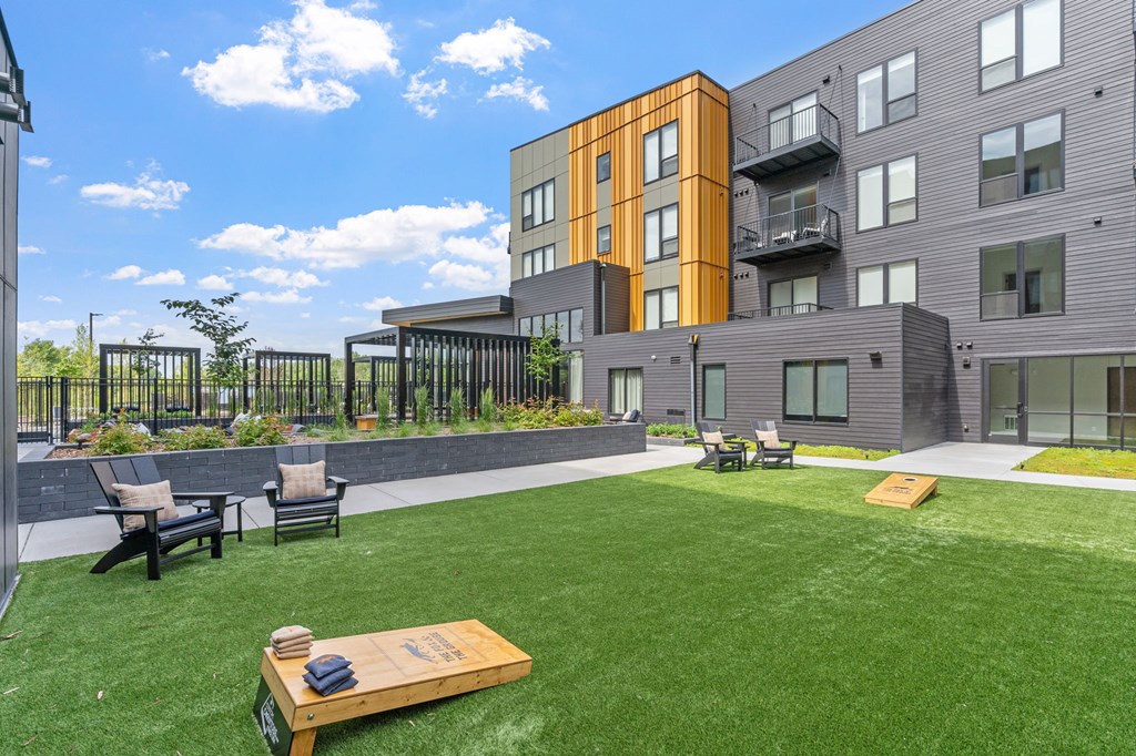 A modern apartment complex with a green lawn and outdoor furniture.