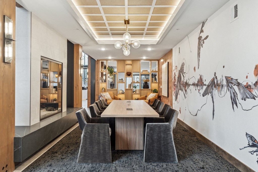A conference room with a long table surrounded by chairs and a wall mural of birds.