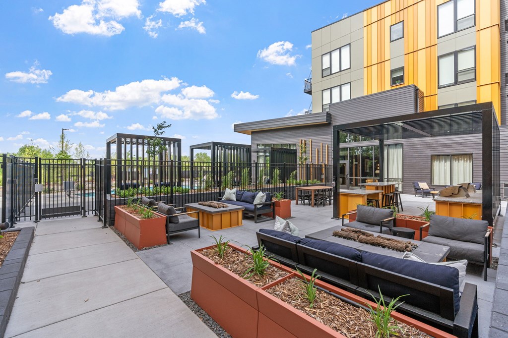 A modern outdoor seating area with a black metal fence and orange planters.