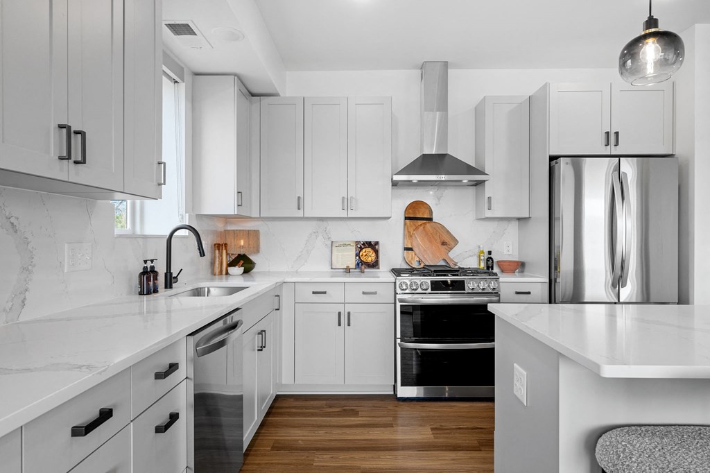 a white kitchen with stainless steel appliances and white counters