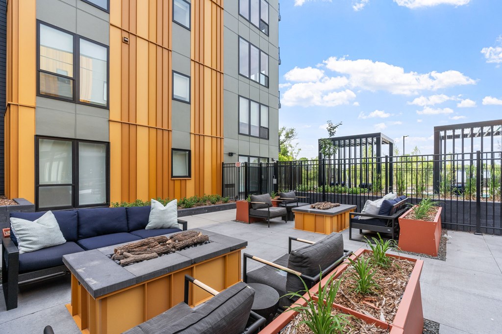 A patio area with a black table and chairs, a couch, and a fire pit.